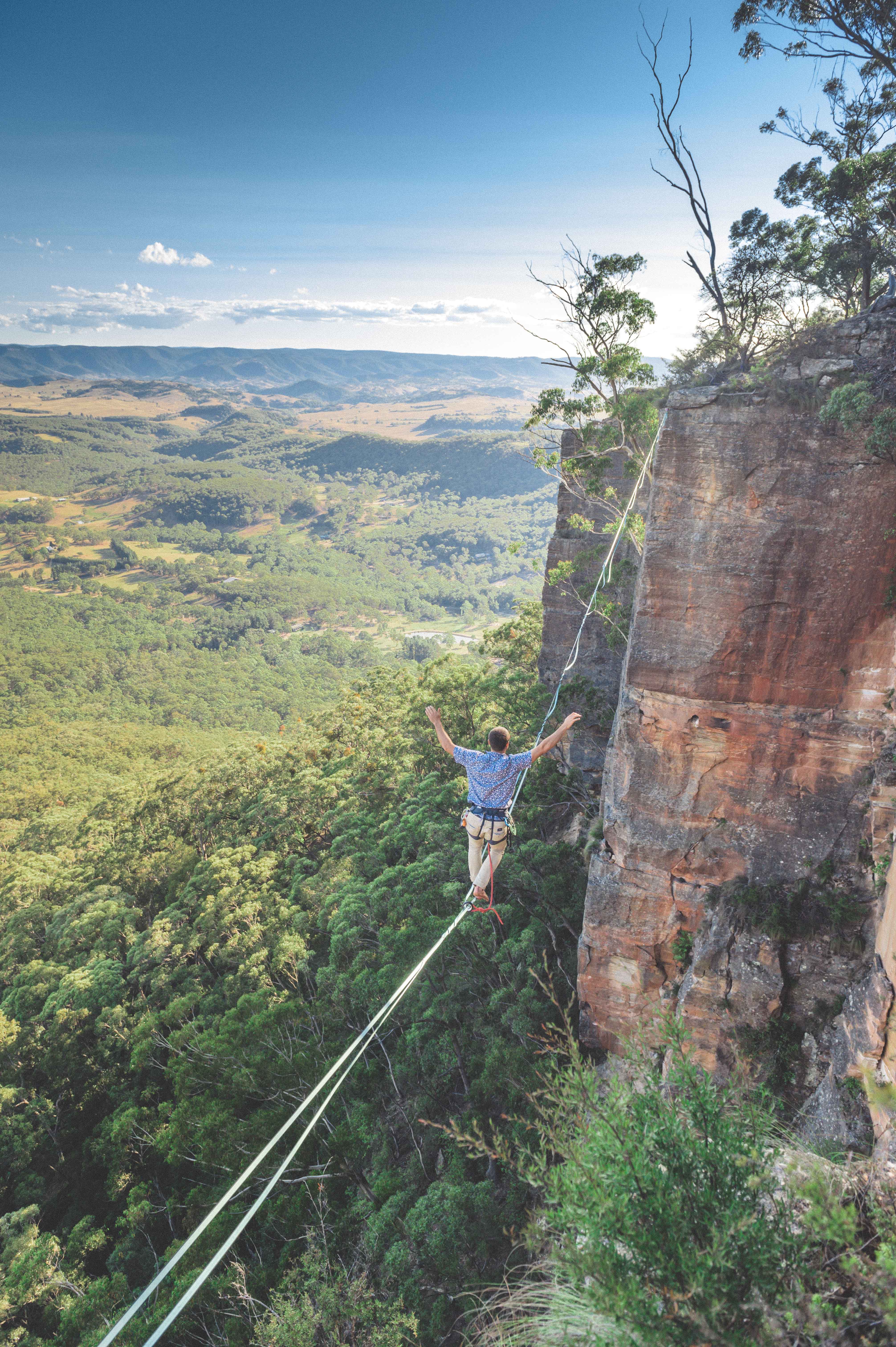 man walking on tightrope with arms outstretched over a canyon